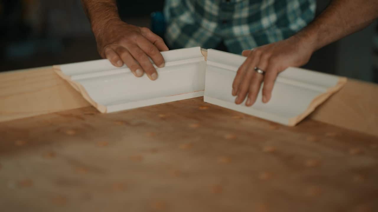 Person showing how piece of moulding might fit together