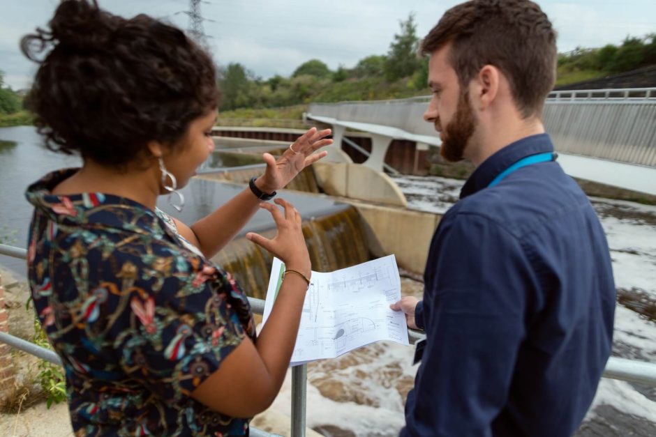 Two people talking through plans on a construction site