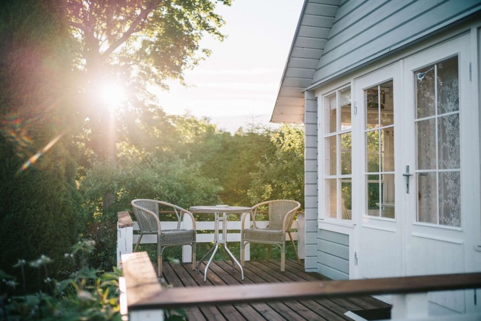 White wooden house with an outdoor deck overlooking the yard