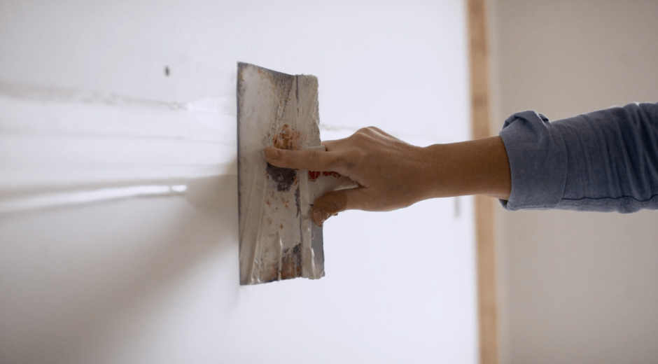 Close-up of hand moving drywall hawk across wall