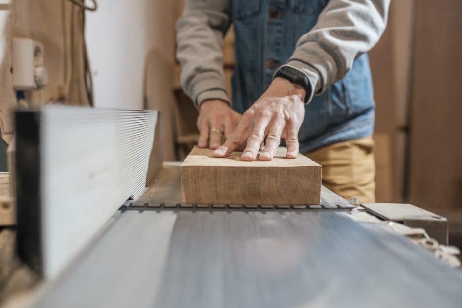 Woodwork and furniture making concept. Carpenter in the workshop processes wood planks on a grinder