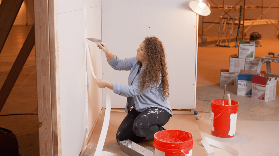 Drywall finisher tapes a butt joint with paper tape