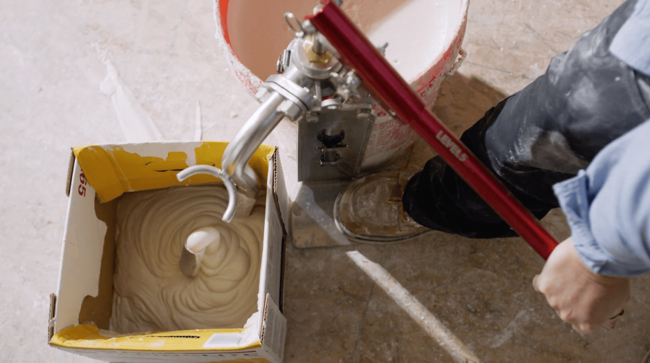 Drywall contractor filling an automatic taper with taping mud