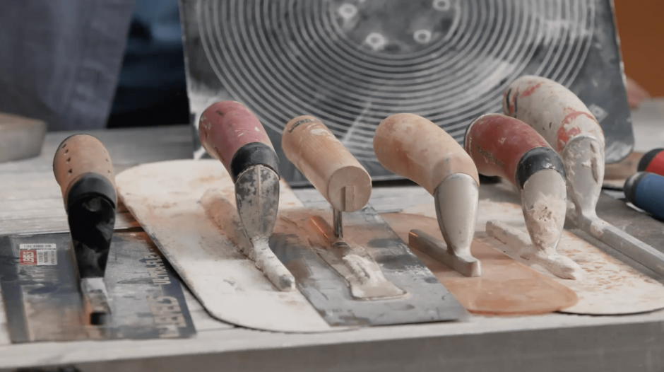 A row of various drywall mudding knives lined up on a table