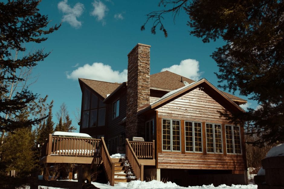 brown house with wooden deck surrounded by trees