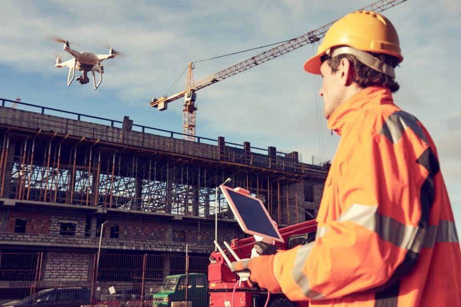 Construction worker operating drone over job site