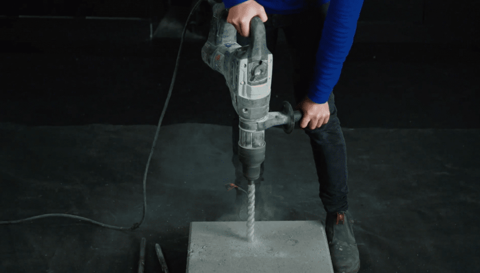 Plumber drilling into a slab of concrete