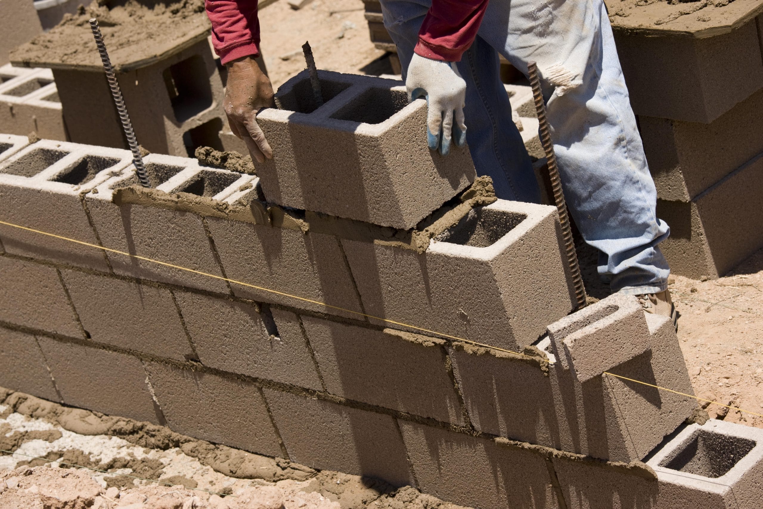 Worker building cinder block wall in desert setting