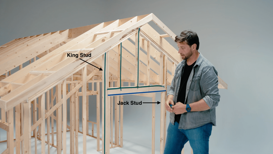 Builder points out jack stud and king stud on miniature house frame