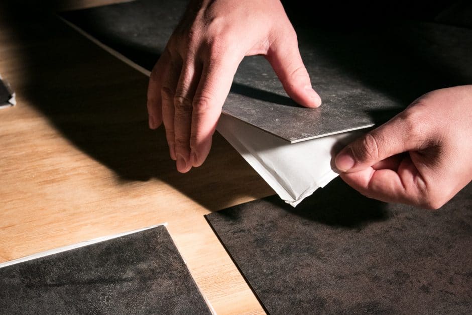 Removing backing from peel and stick vinyl flooring tiles.