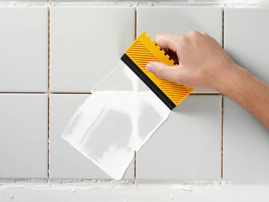 Close-up of worker spreading grout over tile