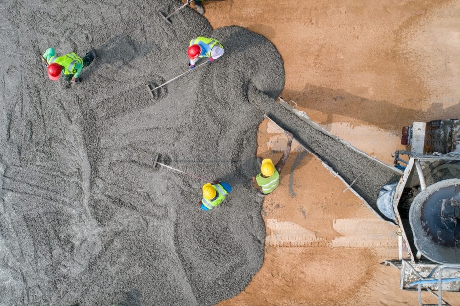 A construction worker pouring a wet concret at road construction site