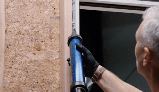 Carpenter applies sealant to door frame