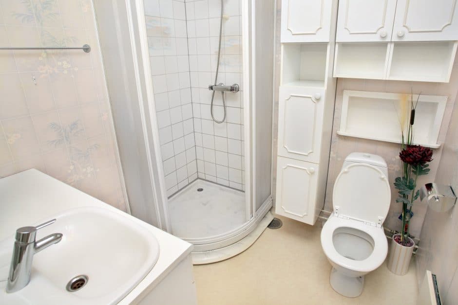 interior of small white bathroom with sink, shower with shower pan, and toilet