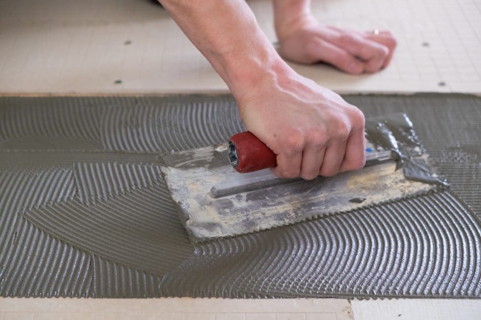 Tile setter laying down thinset for a tiling project during a major house renovation.